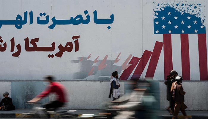 Dumaan ang mga miyembro ng Taliban sa isang mural na naglalarawan ng watawat ng US sa unang anibersaryo ng pag-alis ng mga tropang pinamumunuan ng US mula sa Afghanistan, sa Kabul noong Agosto 31, 2022. — AFP