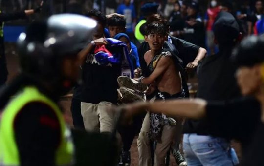 Tumatakbo ang mga kabataang lalaki habang nagpapaputok ng tear gas ang pulis na nag-trigger ng stampede sa Indonesian football stadium noong Sabado ng gabi.  — AFP