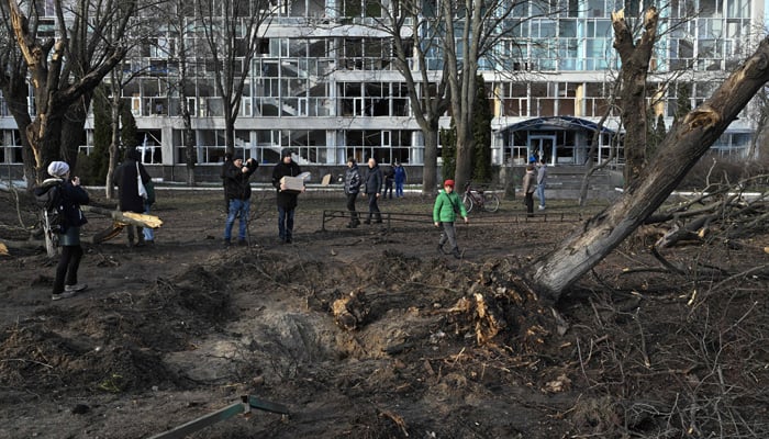 Tinitingnan ng mga bystanders ang isang bunganga sa tabi ng isang gusaling pang-edukasyon sa Kyiv noong Enero 1, 2023. — AFP