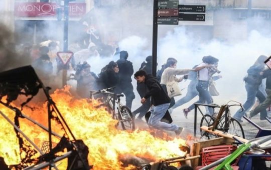 Tumatakbo ang mga nagpoprotesta sa usok ng tear gas sa tabi ng sunog sa kalye sa gilid ng isang demonstrasyon bilang bahagi ng isang pambansang araw ng mga welga at protesta sa Toulouse, southern France, noong Marso 23, 2023. — AFP