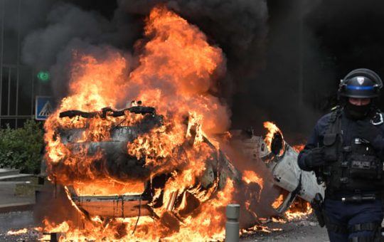 Isang pulis ang dumaan sa isang nasusunog na kotse habang nagprotesta sa Parisian suburb ng Nanterre, noong Hunyo 29, 2023. — AFP